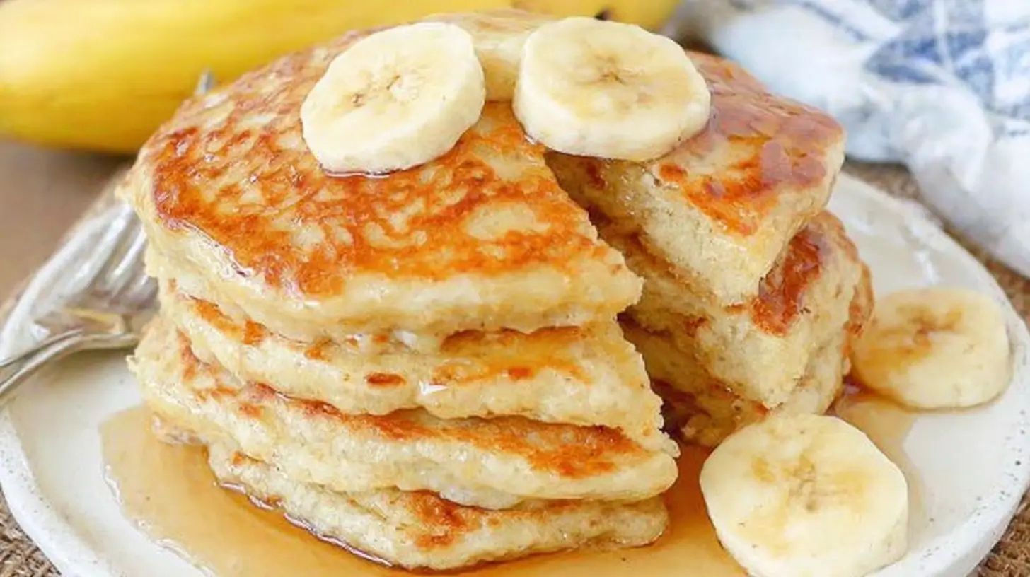 Stack of brown sugar banana pancakes with banana slices and syrup