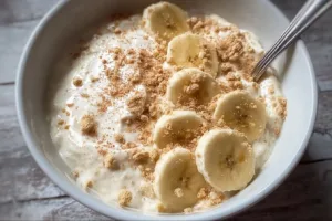 Healthy high protein banana pudding bowl topped with fresh sliced bananas and nuts.