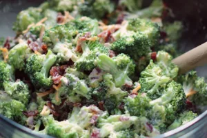 Delicious keto broccoli salad in a white bowl with creamy dressing and toppings